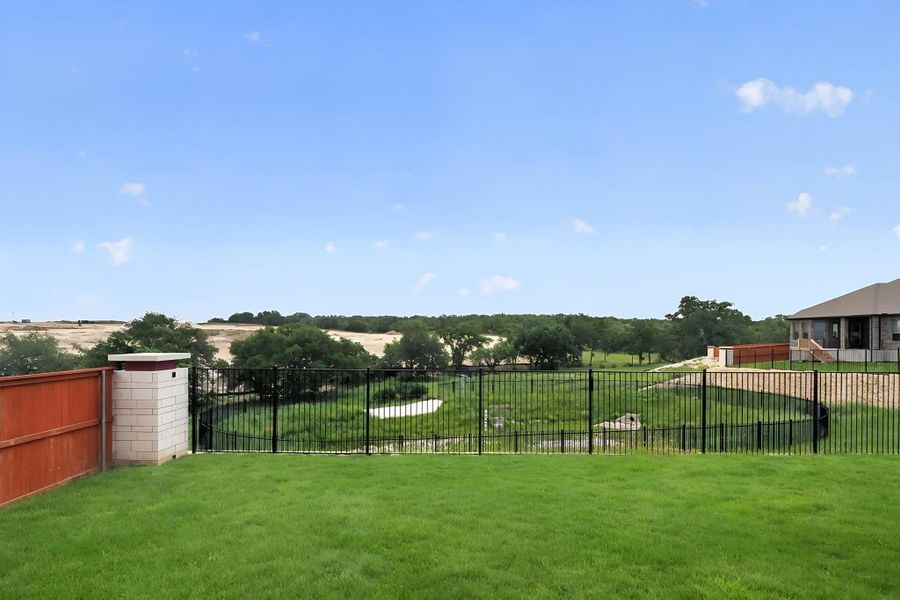 Expansive backyard with a manicured lawn, bordered by a privacy fence and a wrought iron fence Expansive backyard with a manicured lawn, bordered by a privacy fence and a wrought iron fence