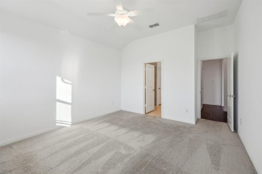 Carpeted Primary Bedroom featuring ceiling fan and lofted ceiling