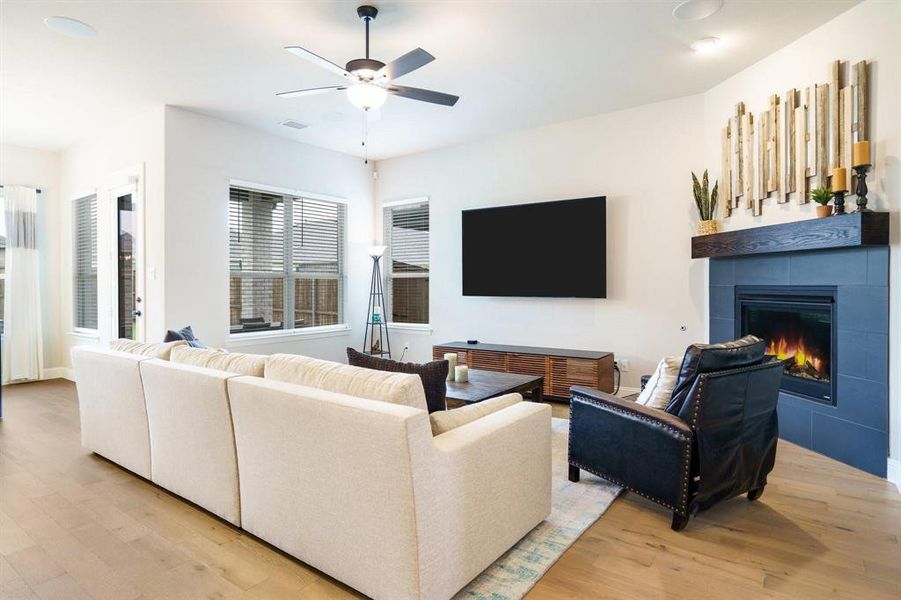Living area with light wood finished floors, ceiling fan, and a tile fireplace Living area with light wood finished floors, ceiling fan, and a tile fireplace