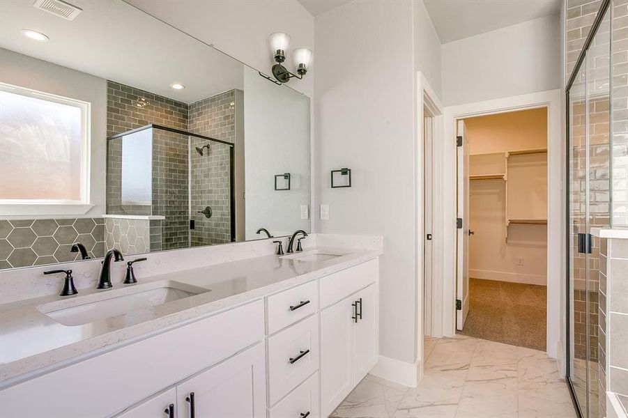 Full bath with a stall shower, light marble finish floors, double vanity, a spacious closet, and tasteful backsplash