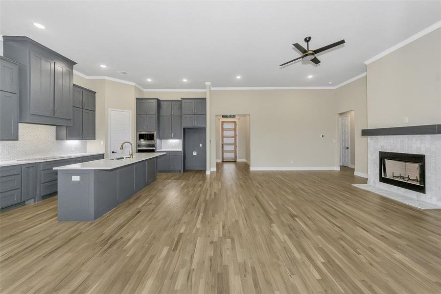 Kitchen featuring sink, a spacious island, light wood-type flooring, gray cabinets, and appliances with stainless steel finishes