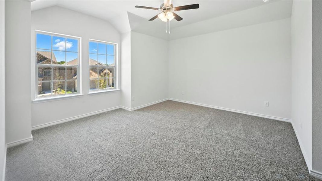 Empty room with carpet flooring, vaulted ceiling, and a ceiling fan