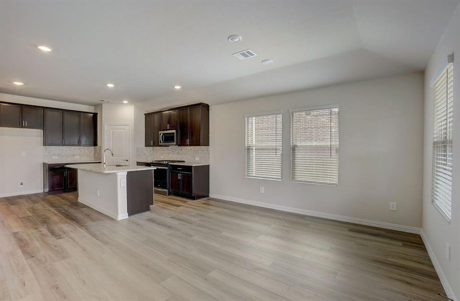 Kitchen with tasteful backsplash, a center island with sink, appliances with stainless steel finishes, light hardwood / wood-style flooring, and a wealth of natural light