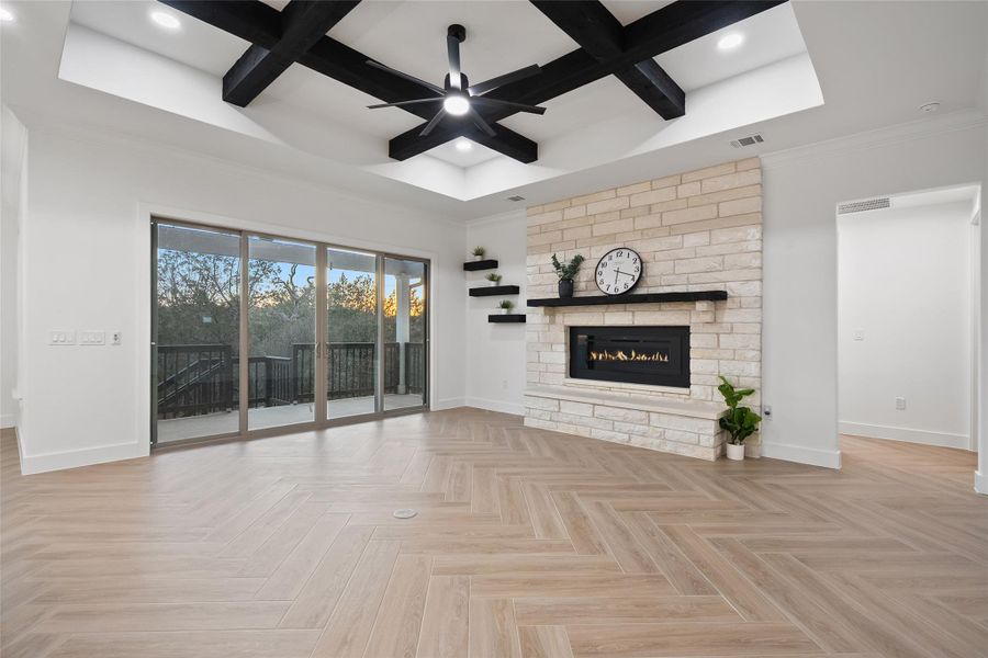 Unfurnished living room with coffered ceiling, a fireplace, beam ceiling, ceiling fan, and recessed lighting