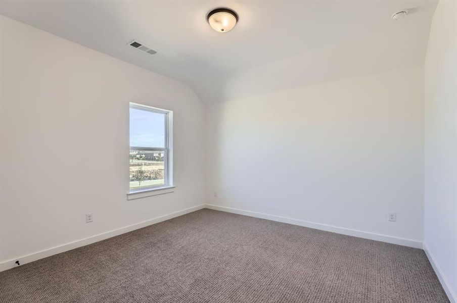 Carpeted empty room featuring lofted ceiling