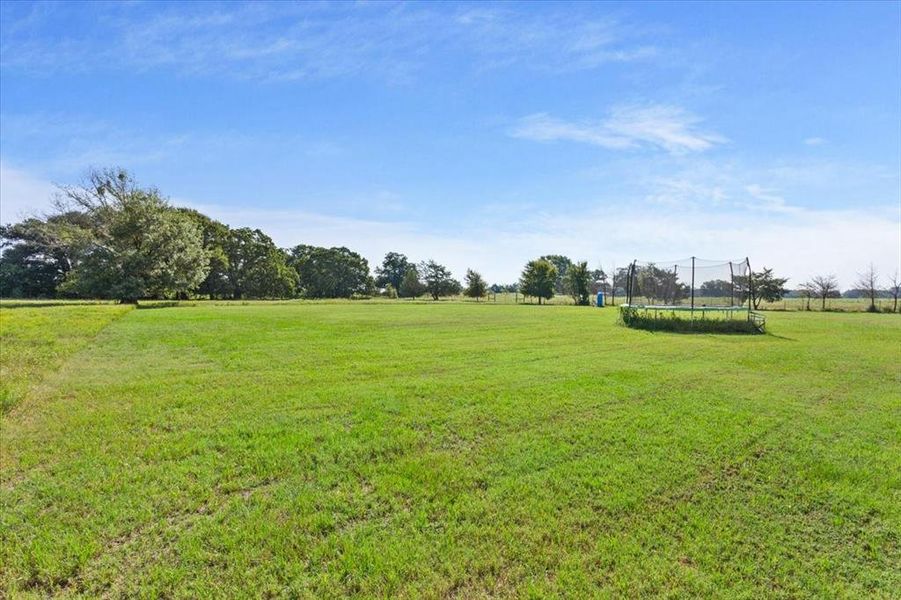 View of home's community featuring a trampoline, a yard, and a view of countryside