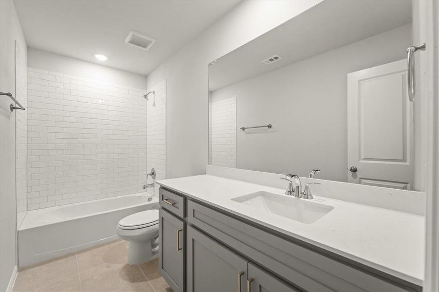 Full bathroom featuring toilet, tiled shower / bath combo, tile patterned floors, and vanity