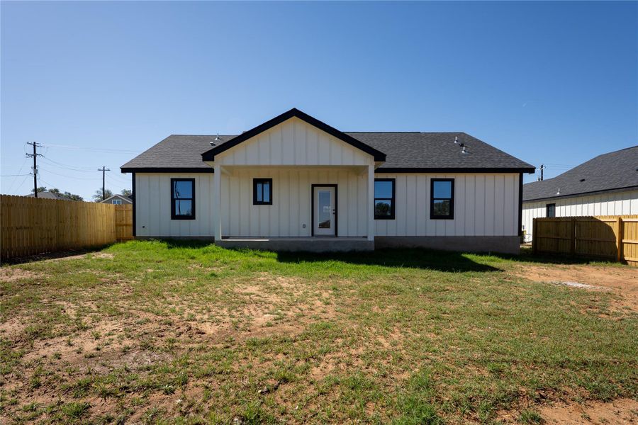 Back of property featuring board and batten siding, a fenced backyard, roof with shingles, and a patio area