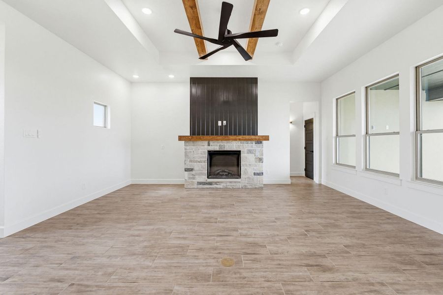 A spacious living area with tall windows, a stone fireplace, and ceiling beams offers a grand impression. A spacious living area with tall windows, a stone fireplace, and ceiling beams offers a grand impression.