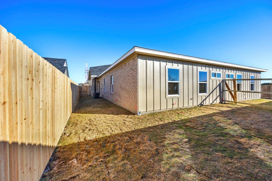 Back of property with brick siding, board and batten siding, and a fenced backyard