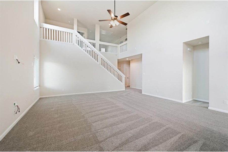 Two-story living area featuring high ceilings, neutral-toned walls, and grey patterned carpeting Two-story living area featuring high ceilings, neutral-toned walls, and grey patterned carpeting