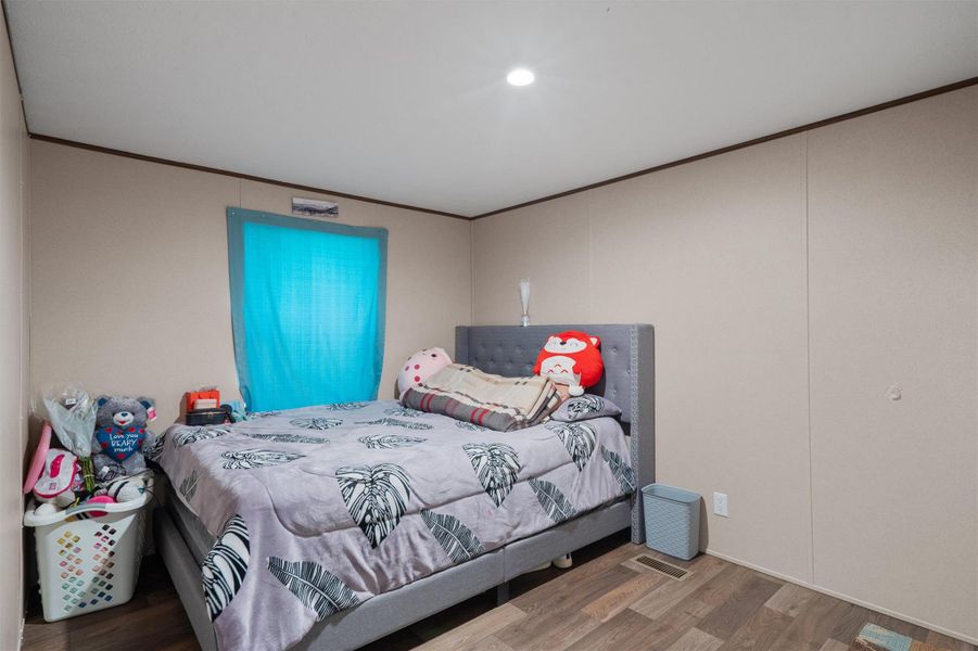 Smooth crown molding and recessed lighting elevate this comfortable, modern bedroom space.
