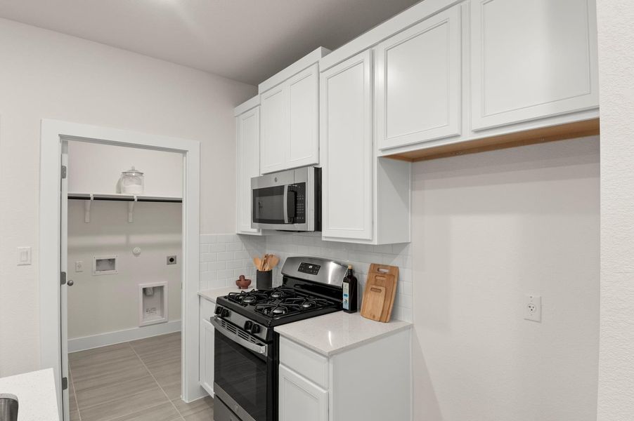 A well-appointed kitchen features a gas range and built-in microwave, complemented by crisp white cabinetry and sleek countertops.