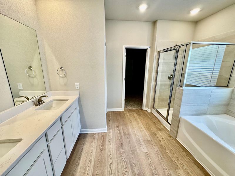 Full bath featuring a shower stall, a bath, double vanity, and light wood-type flooring Full bath featuring a shower stall, a bath, double vanity, and light wood-type flooring
