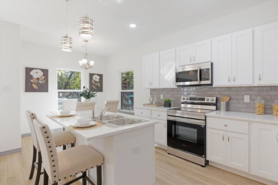 Kitchen featuring decorative light fixtures, white cabinetry, light hardwood / wood-style flooring, and stainless steel appliances