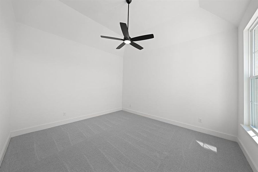 Empty room featuring dark carpet, lofted ceiling, and ceiling fan