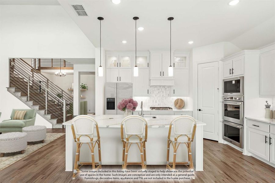Open kitchen with white cabinets, large island with three bar stools, pendant lights, and stainless steel appliances