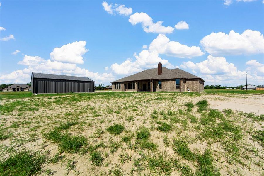 Back of house featuring a pole building, brick siding, a chimney, and an outdoor structure Back of house featuring a pole building, brick siding, a chimney, and an outdoor structure