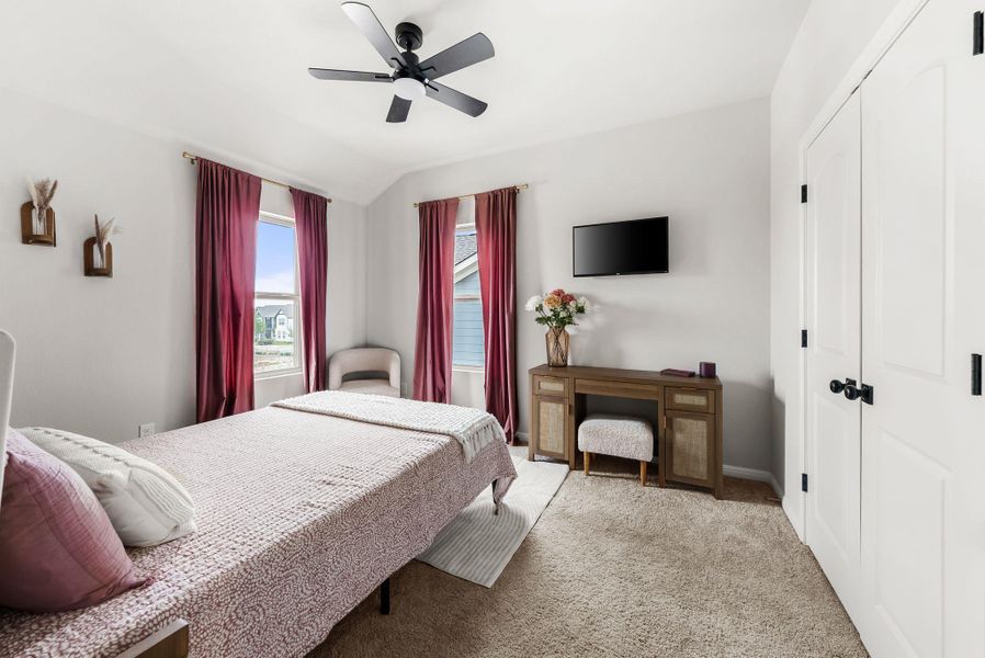 Bedroom with a closet, light colored carpet, ceiling fan, and vaulted ceiling