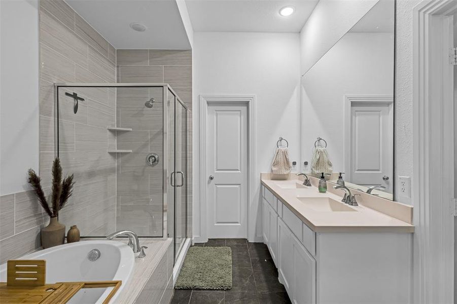 Bathroom with a garden tub, double vanity, a shower stall, and dark tile patterned floors