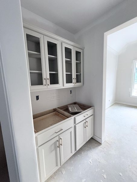 Built-in cabinetry with glass-front upper doors, shaker-style lower doors, and brushed nickel hardware