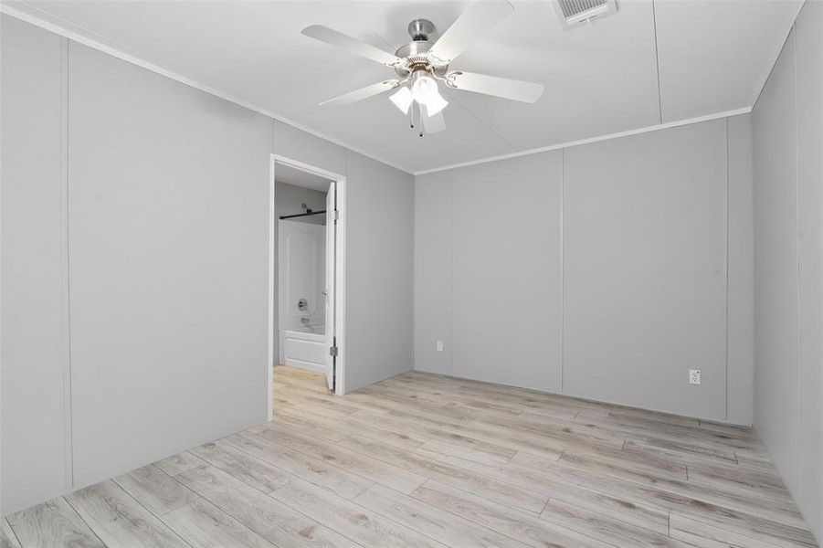 Unfurnished bedroom featuring light wood finished floors, crown molding, a ceiling fan, and connected bathroom Unfurnished bedroom featuring light wood finished floors, crown molding, a ceiling fan, and connected bathroom