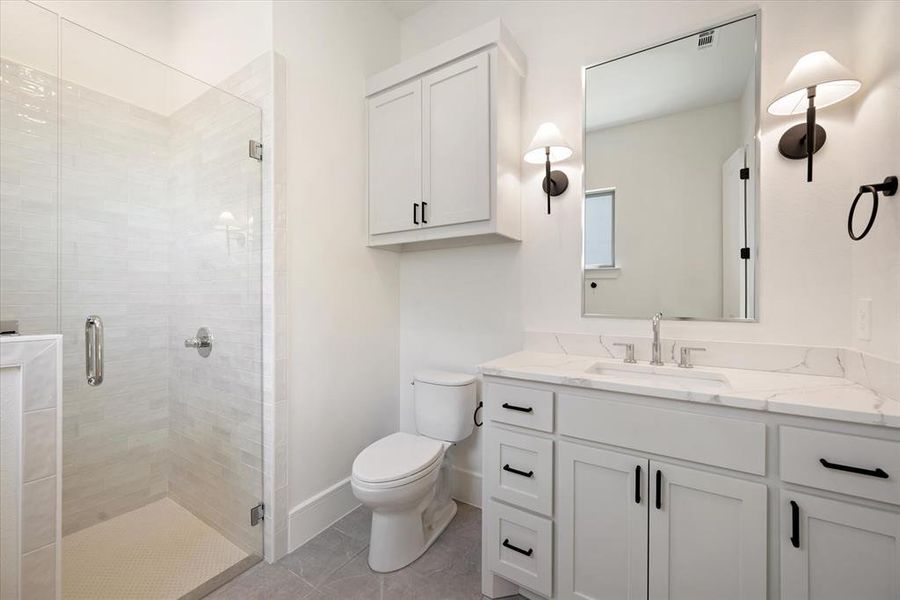 Bathroom with vanity, toilet, tile patterned floors, and a shower with door