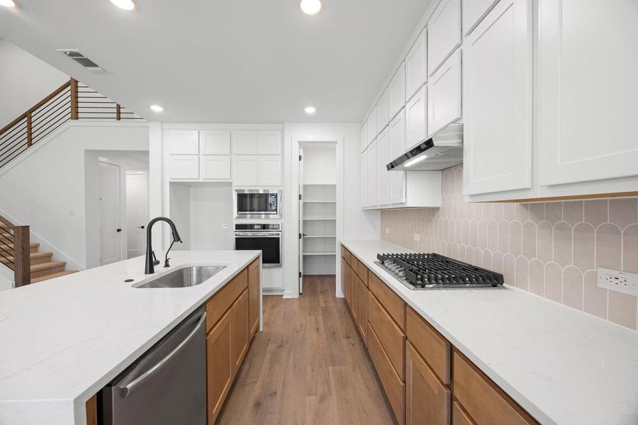 Kitchen featuring dark wood-style flooring, recessed lighting, light stone countertops, appliances with stainless steel finishes, and white cabinetry Kitchen featuring dark wood-style flooring, recessed lighting, light stone countertops, appliances with stainless steel finishes, and white cabinetry