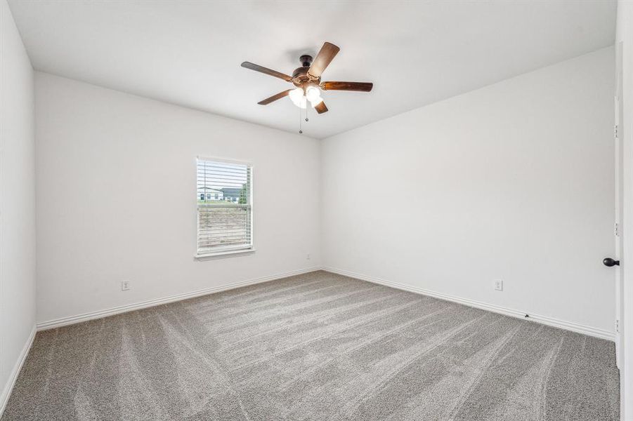 Carpeted spare room featuring ceiling fan