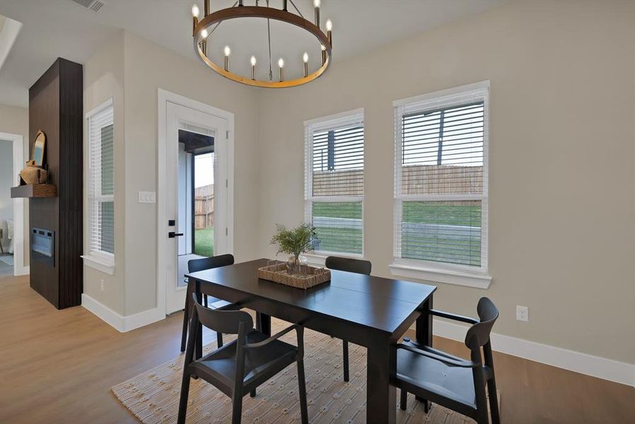 Dining space with a chandelier, light wood finished floors, baseboards, and heating unit