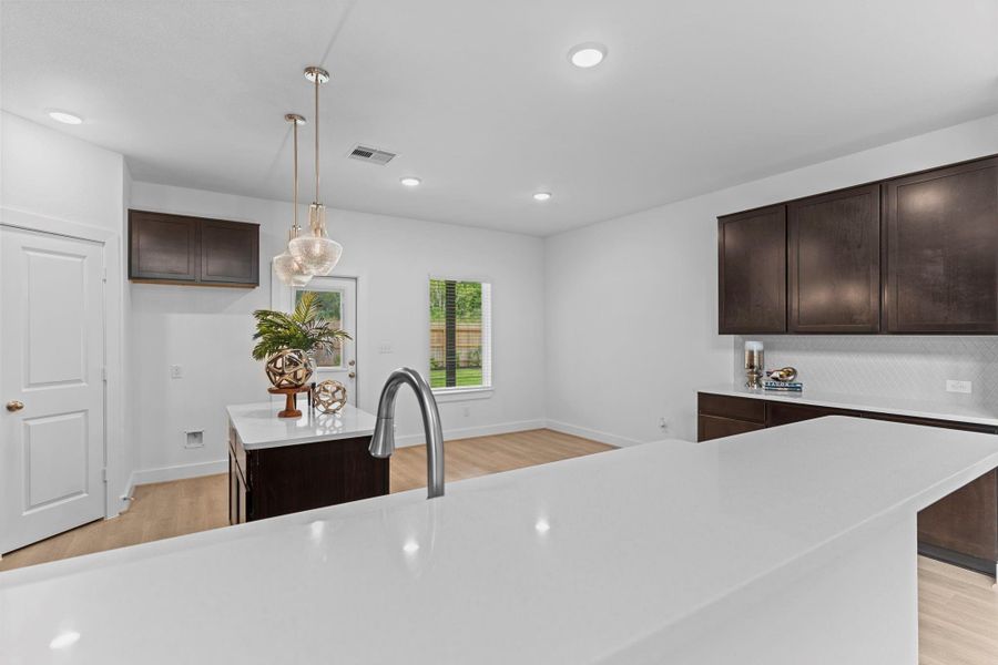 This view highlights the expansive center island with breakfast bar seating, sleek quartz countertops, and a deep undermount sink—ideal for both everyday convenience and effortless entertaining. **Image Representative of Plan Only and May Vary as Built**.