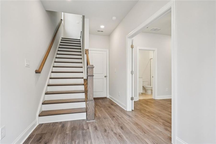 Stairs with wood finished floors and recessed lighting