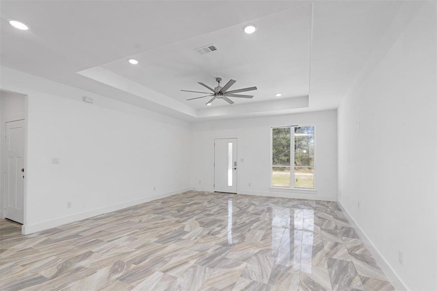 Entrance and living room featuring a tray ceiling and ceiling fan