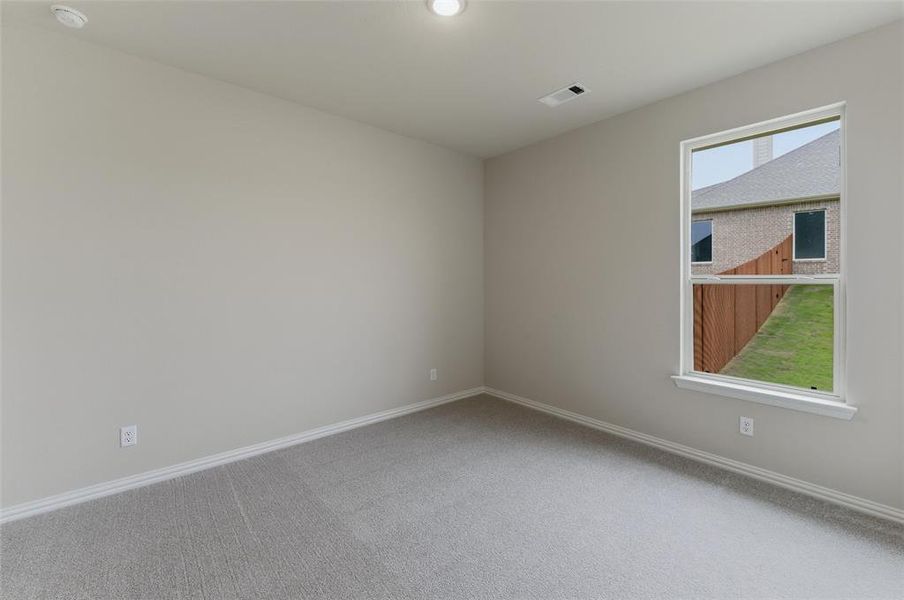 Carpeted interior space featuring a large window, neutral wall paint, white trim, and a ceiling light fixture