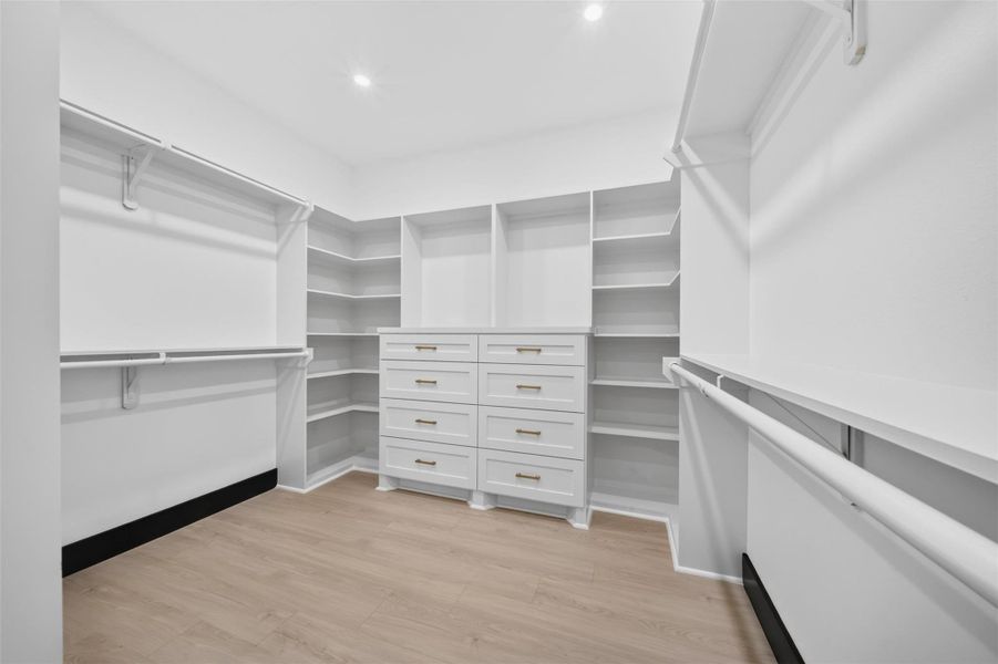 Generous walk in closet with extensive built in shelving and storage space