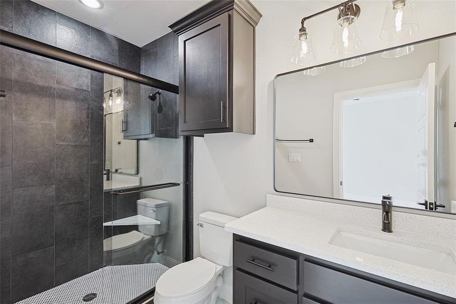 Bathroom with toilet, vanity, a textured ceiling, and walk in shower