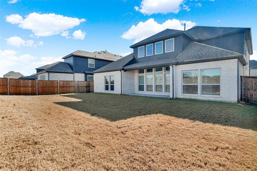 Back of house featuring brick siding, a fenced backyard, a shingled roof, and a patio Back of house featuring brick siding, a fenced backyard, a shingled roof, and a patio