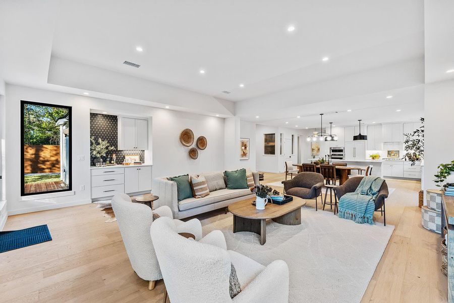 Living room with light wood finished floors, recessed lighting, and a dry bar