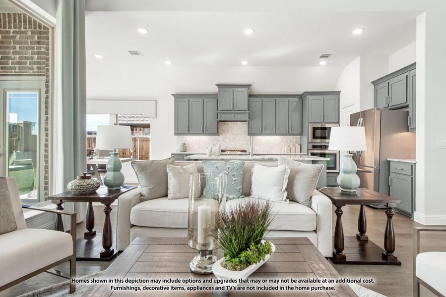 Open-concept living room with white sofa and wood coffee table, open to kitchen with gray cabinets and stainless appliances Open-concept living room with white sofa and wood coffee table, open to kitchen with gray cabinets and stainless appliances