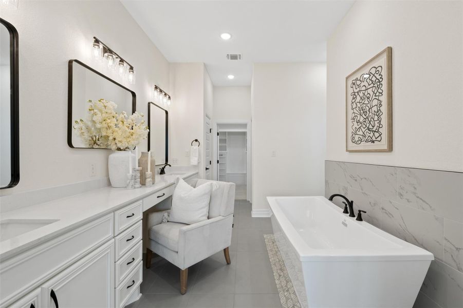 Full bathroom with vanity, a soaking tub, light tile patterned flooring, a walk in closet, and tile walls Full bathroom with vanity, a soaking tub, light tile patterned flooring, a walk in closet, and tile walls
