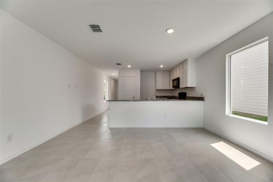 Kitchen featuring light tile patterned flooring, white cabinetry, dark stone counters, and kitchen peninsula