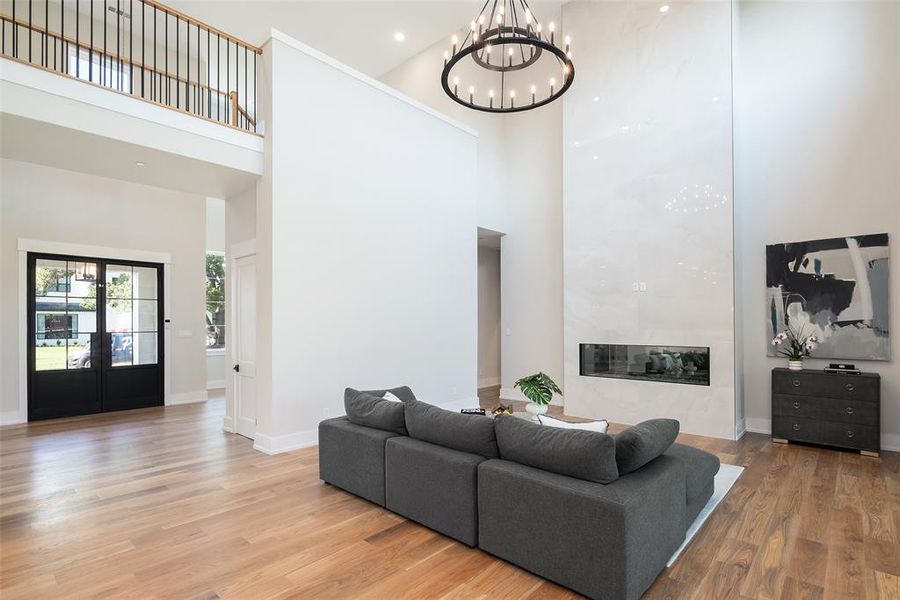 Living room featuring an inviting chandelier, hardwood / wood-style floors, a high ceiling, and french doors