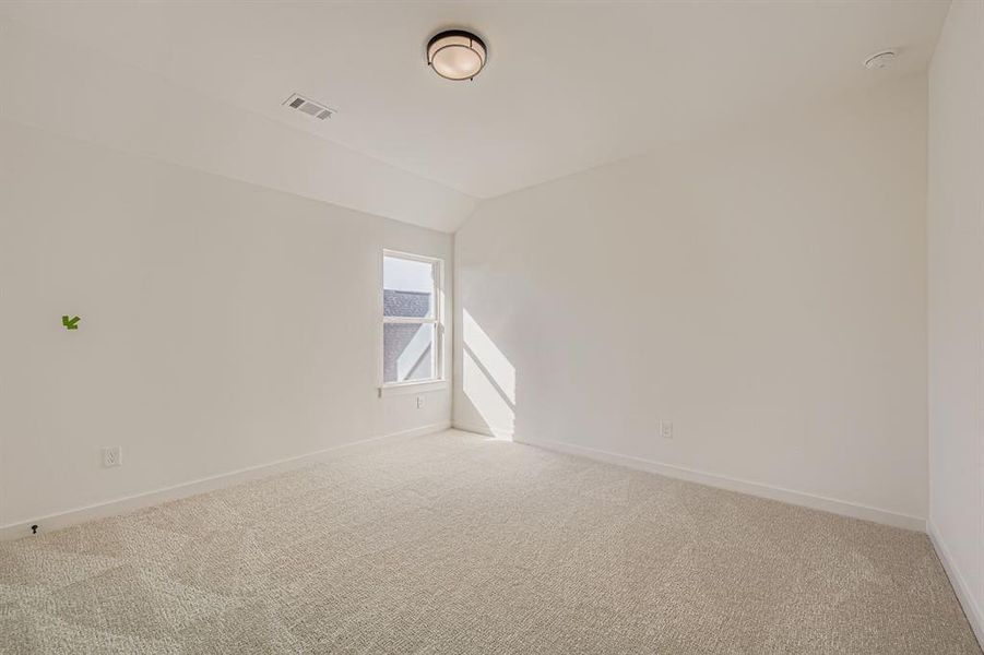 Empty room featuring carpet floors and vaulted ceiling