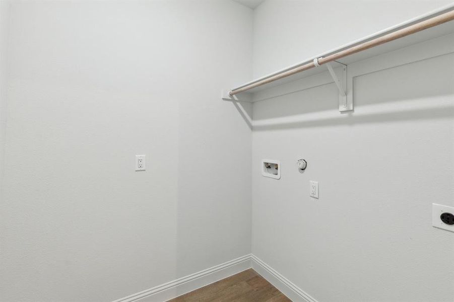 Laundry area with hookup for an electric dryer, washer hookup, hardwood / wood-style flooring.