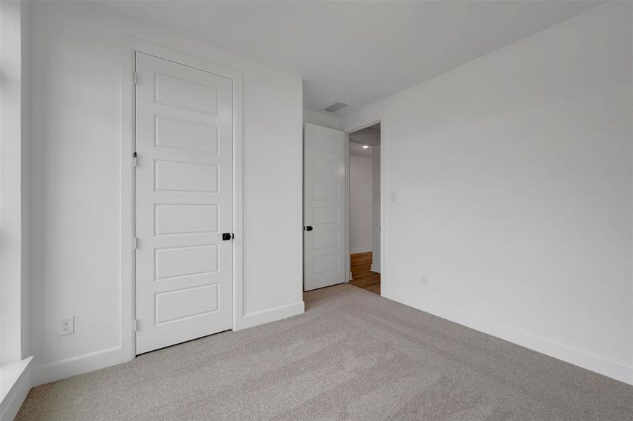 This room features light grey carpet, white walls, and white paneled doors with black hardware