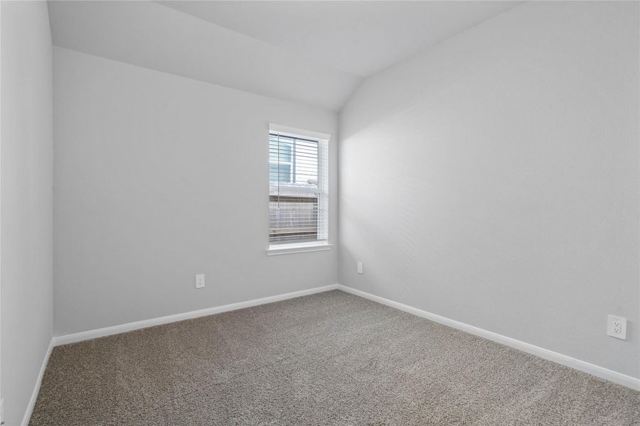 This cozy secondary bedroom offers plush soft carpeting, neutral walls ready for personalization, a sun-filled window with fitted blinds, sloped ceilings, and a spacious closet for all your storage needs.