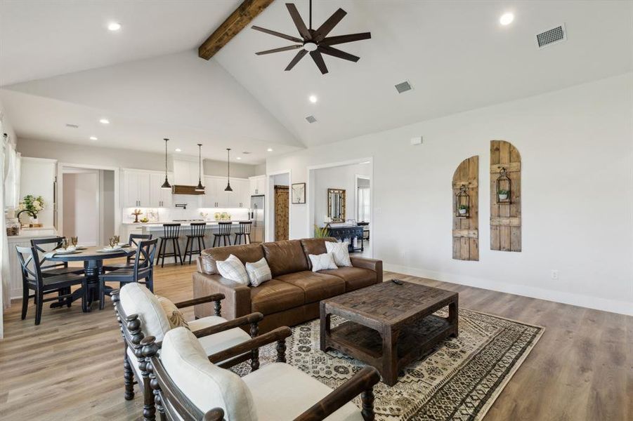 Open-concept living area featuring vaulted ceilings with an exposed wood beam, a ceiling fan, and recessed lighting
