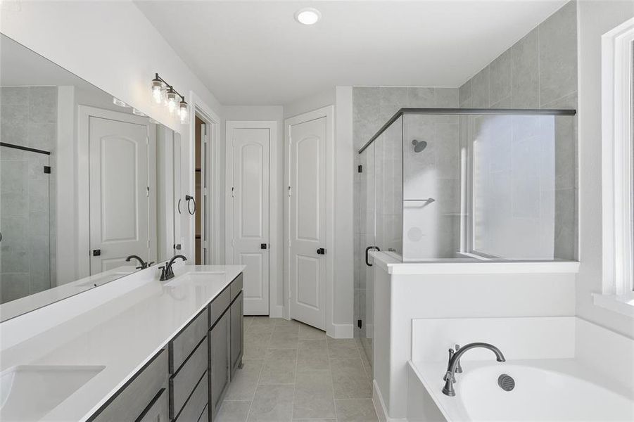 Bathroom with double vanity, a shower stall, a bath, and light tile patterned floors