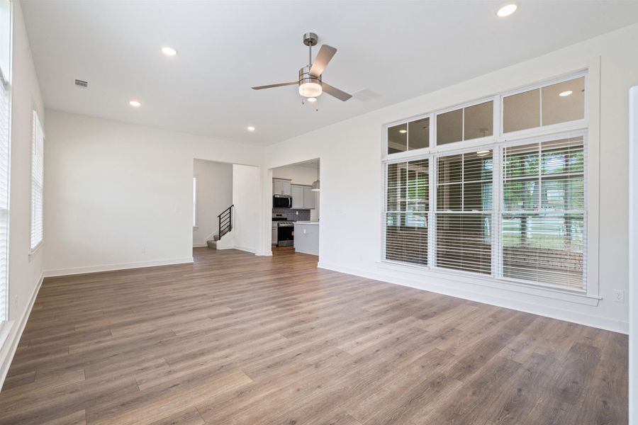 Unfurnished living room featuring ceiling fan, dark wood-type flooring, and recessed lighting