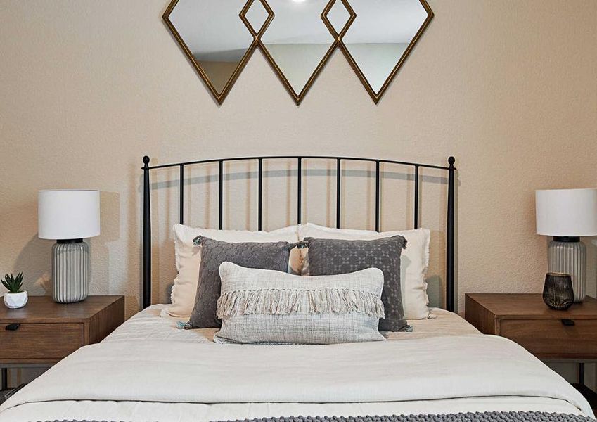 Staged bedroom with large bed, two nightstands, and wall decor.